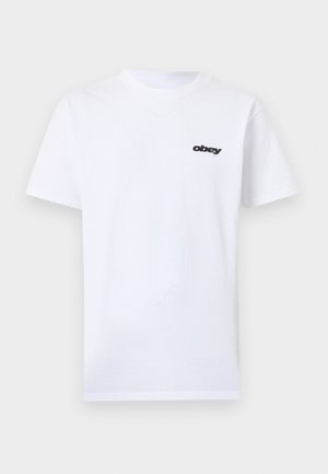 Fehér, rövid ujjú póló kis fekete "obey" logóval a bal mellrészen, elölről látható, egyszerű háttéren.