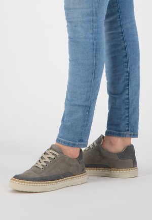 Grijze suède sneakers met een textuurontwerp, crèmekleurige rubberen zool en beige veters. Gestyled met strakke blauwe jeans.