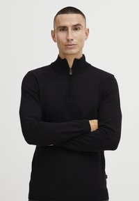 Svart zip-necks genser i en tettsittende design, med ribbestrikkede cuffs og hem, laget av myk strikket stoff, egnet for lagdeling.