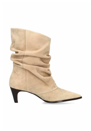 Botte beige en daim souple mi-mollet avec bout pointu et talon noir low incliné.