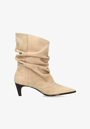 Beige suede slouchy mid-calf boot with pointed toe and low, angled black heel.