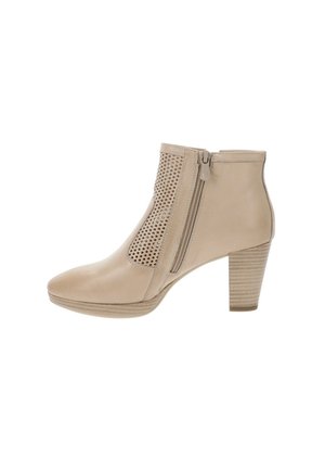 Bottine beige avec un talon empilé de hauteur moyenne, fermeture éclair latérale et panneau perforé sur le côté extérieur pour la ventilation et le style.