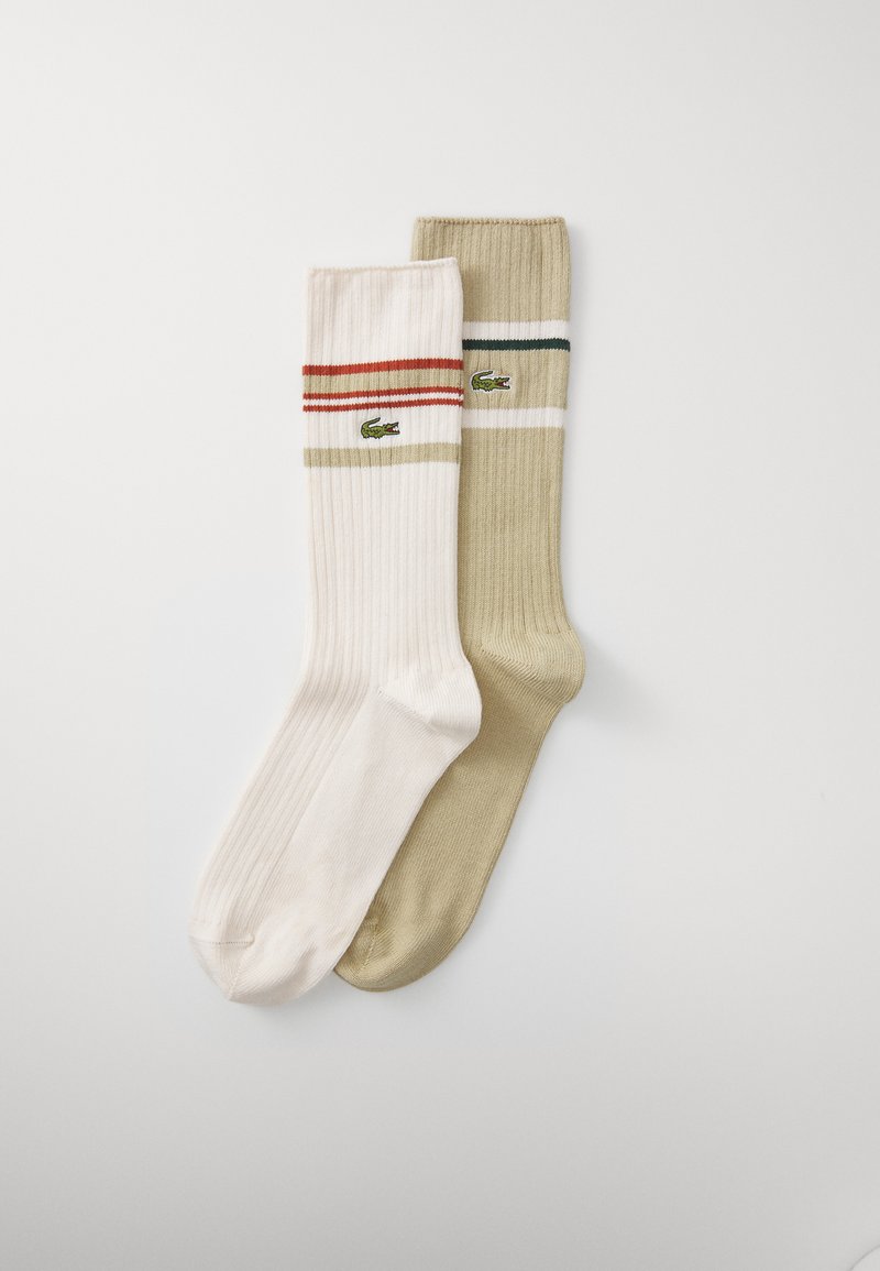 Meias em mistura de algodão nas cores creme e oliva, com textura canelada, riscas contrastantes em vermelho e verde, e um pequeno logótipo verde.