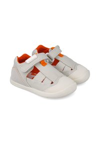 Zapatos de tela grises con detalles en naranja, que cuentan con una correa de velcro, diseño abierto y suela de goma para mayor agarre. Construcción ligera y transpirable.