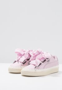 Rosa Ledersneaker mit einem gewellten Design, satinierten Bändern als Schnürsenkel und einer strukturierten Gummisohle. Mit einem grauen Akzentlogo an der Seite.