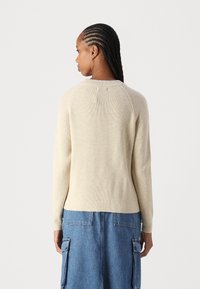 Μπεζ ριγωτό πουλόβερ με στρογγυλή λαιμόκοψη και μακριά μανίκια, κατασκευασμένο από υφασμένο υλικό με υφή,  απεικονίζεται από πίσω.