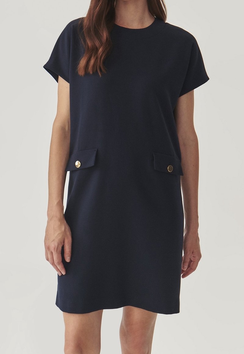 Navy blue short-sleeve dress with a straight cut, featuring two front pockets with gold buttons, made from a smooth fabric.