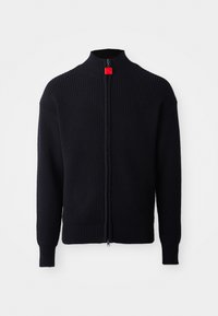 Juoda megzta zip-up švarkas su aukštu apykakle, reliefiniu tekstūru ir raudona akcentu ant užtrauktuko. Turi ilgomis rankovėmis ir prigludusią taliją.