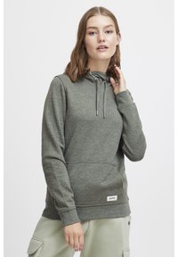 Sudadera con capucha gris hecha de un tejido suave, con un bolsillo canguro, capucha con cordón, puños acanalados y una pequeña etiqueta de logo en el dobladillo.