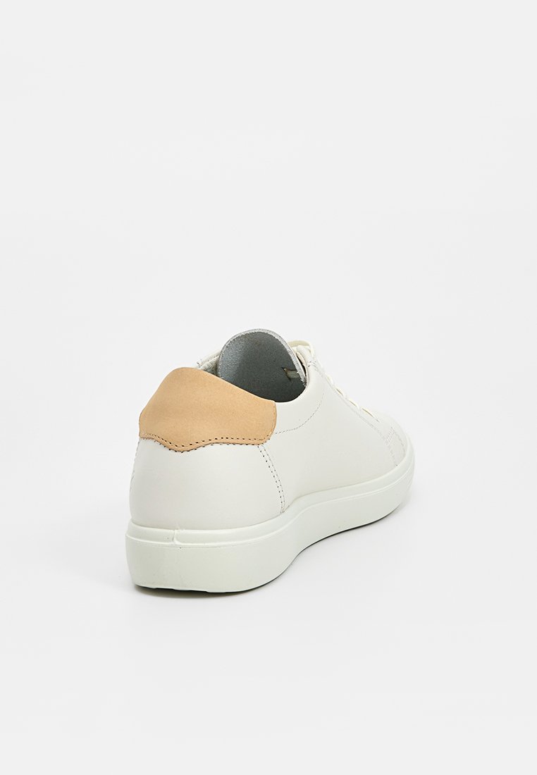 Weiße Low-Top-Sneaker mit beigem Wildleder-Ferseneinsatz, weißer Sohle und Schnürverschluss, von der hinteren linken Winkelansicht auf einem weißen Hintergrund gezeigt.