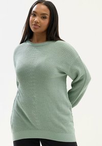 Maglione lavorato a maglia sovradimensionato verde chiaro con un design strutturato, scollo ampio e orlo e polsini a coste. Adatto per un abbigliamento casual.