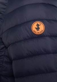 Navy blue puffer jacket featuring a quilted design, smooth texture, and an orange circular patch labeled "SAVE THE DUCK" with a duck silhouette.