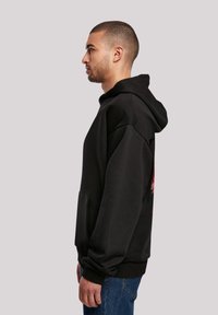 Black hooded sweatshirt with a loose fit, featuring long sleeves and a front pocket. Made of soft material with a solid color design.