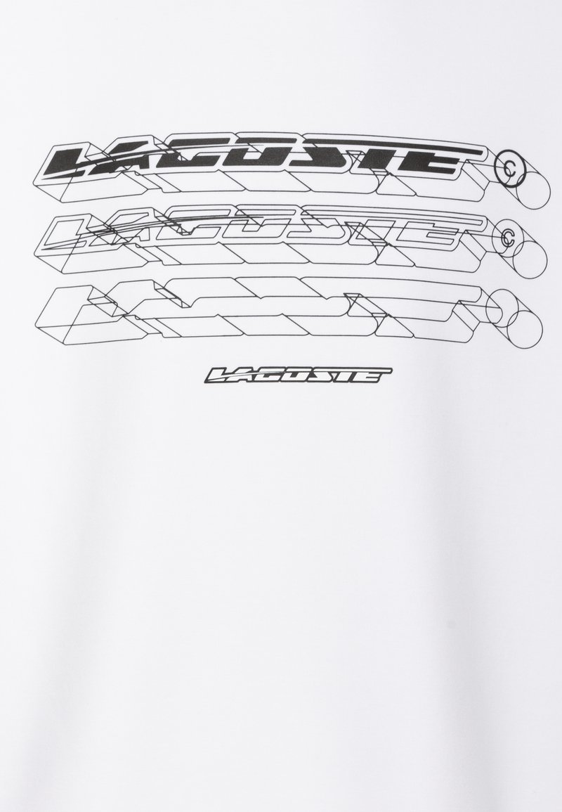 Camiseta blanca con un estampado gráfico negro que presenta el logo "LACOSTE", mostrando múltiples versiones estilizadas en diferentes grosores de línea.