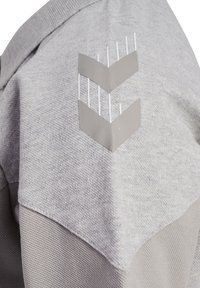 Grå sweatshirt med texturerat tyg och en slät yta, försedd med en geometrisk logotyp i ljusgrått på axeln.
