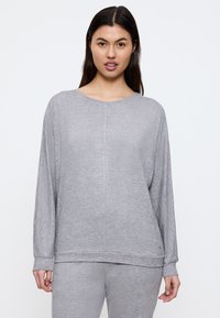 Pullover grigio chiaro a maniche lunghe realizzato in un tessuto morbido, con scollo rotondo, vestibilità rilassata e polsini a costine, abbinato a pantaloni coordinati.