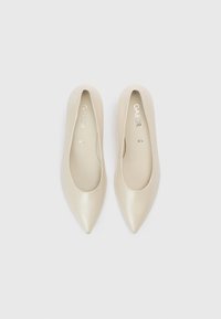 Μπεζ μπαλαρίνες με μυτερή μύτη, λείο δερμάτινο φινίρισμα και μινιμαλιστικό σχεδιασμό. Εσωτερικά διαθέτουν τυπωμένο όνομα επωνυμίας και μέγεθος.