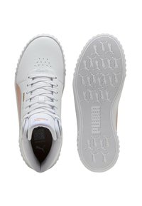 Witte Puma sneaker met beige zijstreep, veters en geperforeerde neus, weergegeven vanuit bovenaanzicht en zool met Puma-logo loopvlakpatroon.
