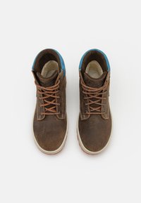 Botas de tobillo de ante marrón con acentos azules, que cuentan con cordones naranjas, una suela de goma blanca y detalles de costura en la parte superior.
