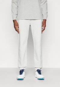 Ανοιχτό γκρι φούτερ και ταιριαστά tapered παντελόνια φόρμας, φτιαγμένα από μαλακό ύφασμα. Διαθέτει ελαστικές μανσέτες και λευκά αθλητικά παπούτσια με μπλε λεπτομέρειες.