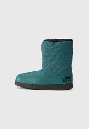 Teal ankle boot with quilted heart pattern, black lining, flat sole, and contrasting "LOVE ME" text on the side. Rubber outsole for traction.
