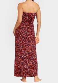 Maxi šaty bez ramínek v námořnické modři s červeným listovým vzorem. Elastický pas, délka ke kotníkům se střihem rovného lemu, vyrobené z lehké látky.