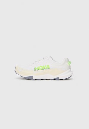 Baskets de sport blanches avec un logo "HOKA" vert, dessus texturé, semelle rembourrée et semelle extérieure grise. Lacets et léger rembourrage au niveau du col.