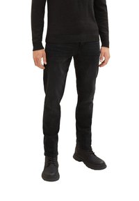 Schwarze Denim-Jeans im Slim-Fit-Stil, mit leicht verblasster Textur, kombiniert mit schwarzen Schnürstiefeln. Einfacher, lässiger Stil.
