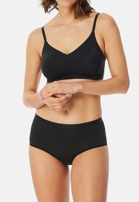 Zwarte draadloze bh met verstelbare bandjes, v-hals ontwerp, gladde stof, gecombineerd met bijpassende zwarte high-waisted slip in vergelijkbaar materiaal.