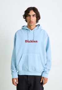 Light blue hoodie made from soft fabric, featuring a front pocket and a red "Dickies." logo on the chest. Ribbed cuffs and hem.