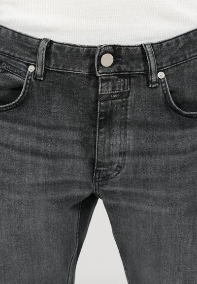 Jean en denim gris foncé avec un design classique à cinq poches, fermeture à bouton en métal et détails de couture subtils le long des coutures.