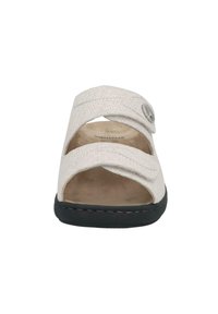 Light beige slide sandals with cross straps, textured fabric upper, soft inner lining, and black rubber outsole with subtle stitching.