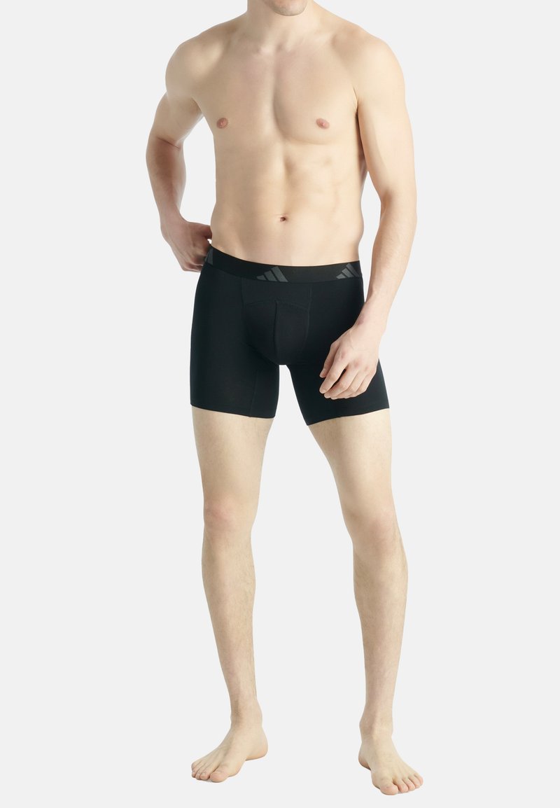 Zwarte boxers met een zachte elastische tailleband, voorzien van een subtiele textuur en een voorvak. De stof lijkt soepel en aangesloten.