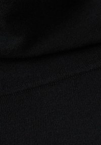 Tela negra de punto con una textura suave y un dobladillo acanalado. El material parece ser suave y está tejido de forma densa sin ningún patrón.