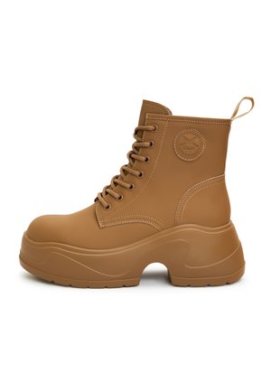 Botas de tobillo sintéticas marrones con cordones, tacón grueso, punta redonda, parche de logo lateral y detalle de costura en contraste.