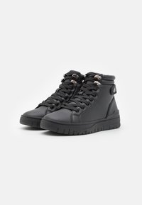 Zapatillas alta negras de cuero liso con puntera redonda, cordones en la parte delantera, ojales metálicos y suela de goma texturizada.