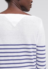Biała i granatowa sweter w paski z szerokim dekoltem, miękka w dotyku, z tyłem w kształcie litery V. Casualny design na co dzień.