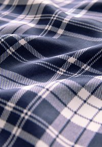 Navy blue plaid fabric with white and light blue stripes, featuring a soft texture and a wavy pattern due to draping.