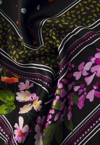 Tela negra con un estampado floral que presenta flores en tonos rosa, naranja y azul, bordeada por rayas blancas y de colores, creando un aspecto texturizado.