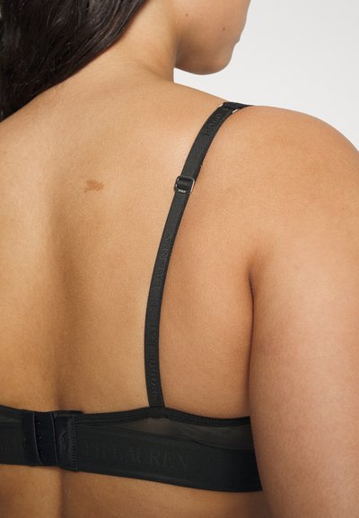 Sostén negro con tirantes ajustables y una banda texturizada con detalles de logo. Tejido suave con un panel superior transparente.