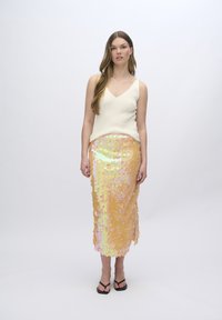 Crème tanktop met een V-hals, gecombineerd met een knielange rok versierd met sequins in tinten geel en roze, met een zijsplit.