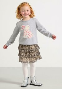 Maglione grigio con un coniglietto dalle orecchie rosa e cuori, abbinato a una gonna a strati con stampa leopardata, stivaletti neri e argentati.