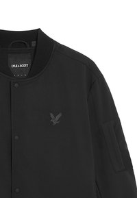 Giubbotto bomber nero con colletto a costine, presenta un sottile logo ad aquila in rilievo sul petto e una tasca laterale sulla manica.