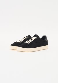 Sneakers in suede nero con lacci crema, punta rotonda e suola in gomma crema. Design minimalista con superficie liscia e senza motivi visibili.