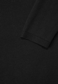 Svart stickad tröja med en texturerad tygstruktur och ribbade ärmslut. Designen inkluderar en närbild av fin sömnad och en slät finish.