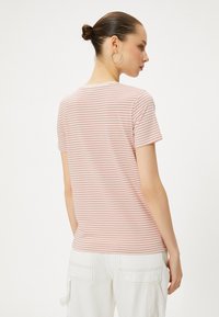 Stripet t-shirt i lys pink og hvid, lavet af blød bomuld, med korte ærmer og almindelig pasform. Bagfra ses en diskret rund halsudskæring.