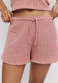 Rosa ribbatta stickade shorts med dragsko i midjan, med en mjuk textur och en vågig nederkant, lämpliga för avslappnad stil.