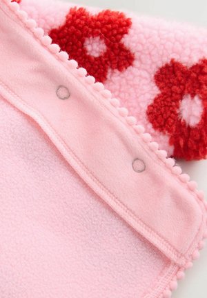 Couverture en polaire rose avec une partie supérieure texturée ornée de motifs floraux rouges, bordée de détails en pompons et de fermetures à pression sur le bord.