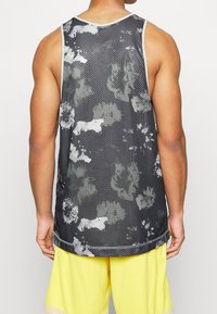 Black mesh tank top featuring a floral pattern in grey and white, with a round neckline and contrasting trim. Full-length back view.