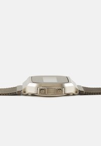 Montre numérique en ton argent avec un cadran carré, bracelet en maille texturée, deux boutons latéraux et une lunette lisse et polie.